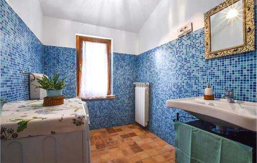W wyłożonej niebieskimi kafelkami łazience znajduje się umywalka i lustro. w obiekcie 4 Bedroom Cozy Home In Lungro w mieście Lungro