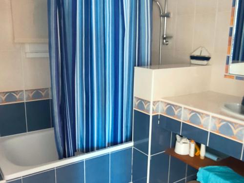 La salle de bains est pourvue d'un rideau de douche bleu et d'un lavabo. dans l'établissement Maison avec 2 chambres, piscine privée et jardin clos à Saint-Jean-de-Monts - FR-1-323-439, à Saint-Jean-de-Monts