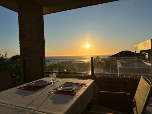 a table with a glass of wine and a view of the sunset at Sunny Ocean View Retreat in Perth