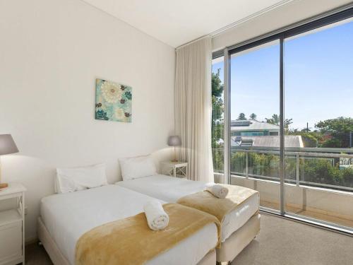 a white bedroom with a bed and a large window at Aqua Viva 2 in The Entrance