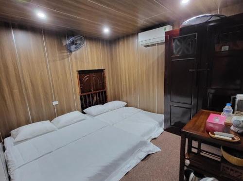 a bedroom with a white bed and a wooden wall at Thac Tien Village Ba Vi in Ba Vì