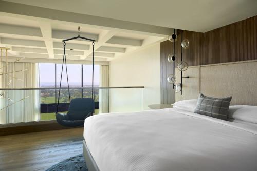 a bedroom with a large white bed and a blue chair at VEA Newport Beach, a Marriott Resort & Spa in Newport Beach
