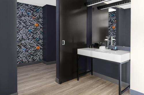 La salle de bains est pourvue d'un lavabo et d'un miroir. dans l'établissement Aloft Glendale at Westgate, à Glendale