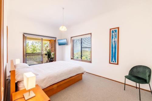 une chambre avec un lit, une chaise et une fenêtre dans l'établissement Casa Carinho, 24 Wallawa Rd - spectacular water views, pet friendly, air con and Wi-Fi, à Nelson Bay