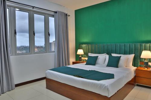 a bedroom with a large bed with a green wall at EMERALD@On320 in Colombo