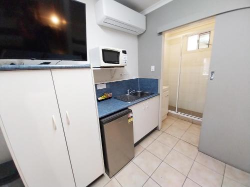 a small kitchen with a sink and a microwave at Tropic Coast Motel in Mackay