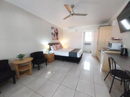 a small room with a bed and a kitchen with a table at Tropic Coast Motel in Mackay