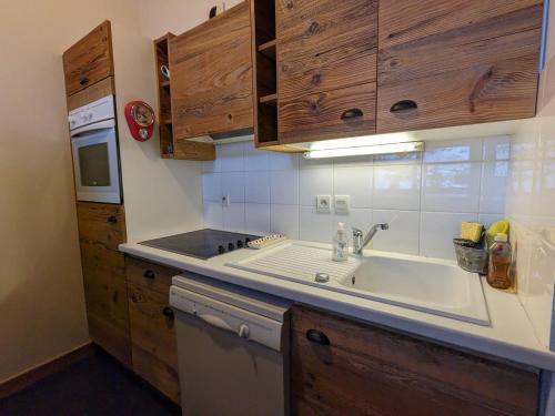 une cuisine avec un évier et des armoires en bois dans l'établissement Appartement cosy au pied des pistes avec balcon et parking couvert - FR-1-459-225, à La Clusaz