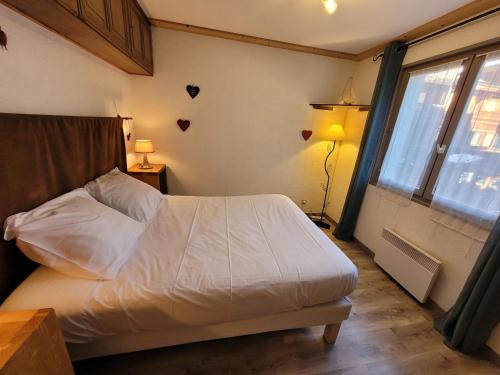 une chambre avec un lit blanc et une fenêtre dans l'établissement Appartement lumineux et bien agencé en plein centre, proche pistes, pour 2 à 4 personnes - FR-1-598-157, aux Gets