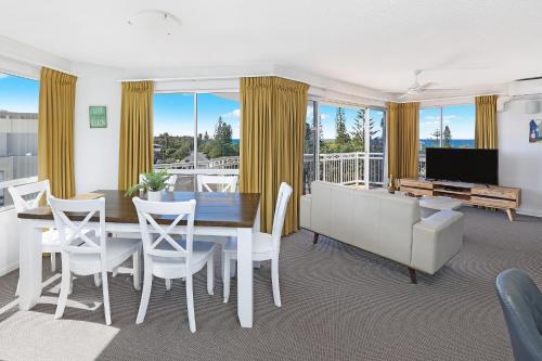 a dining room with a table and a couch at Beachside Resort Kawana Waters in Buddina