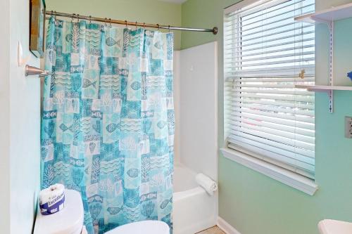 La salle de bains est pourvue d'un rideau de douche bleu et de toilettes. dans l'établissement South Harbour 2A, à Pensacola Beach