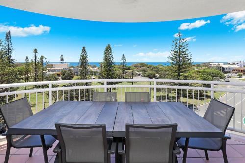 a large wooden table on a balcony with chairs at Beachside Resort Kawana Waters in Buddina