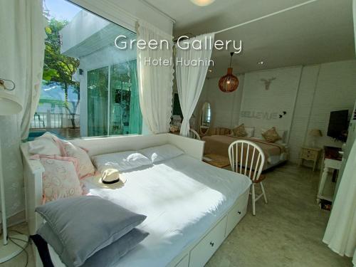 a bedroom with a white bed and a living room at Green Gallery Beach Boutique Hotel in Hua Hin