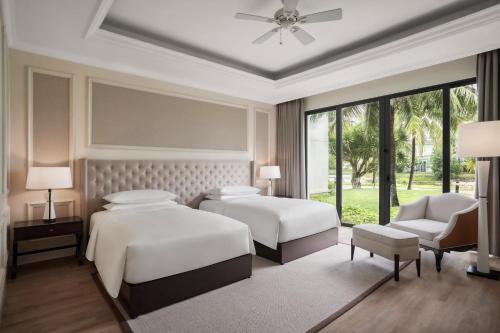 a bedroom with two beds and a couch and a fan at Sheraton Phu Quoc Long Beach Resort in Phu Quoc