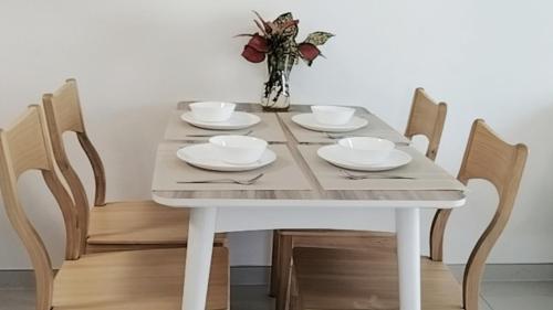 a table with four chairs and a white table with plates and bowls at Forest森林城市01 in Kampong Pok Kechil