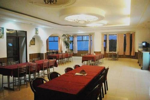 una sala da pranzo con tavoli e sedie rossi e finestre di Aromo's S N Resort a Dharamshala