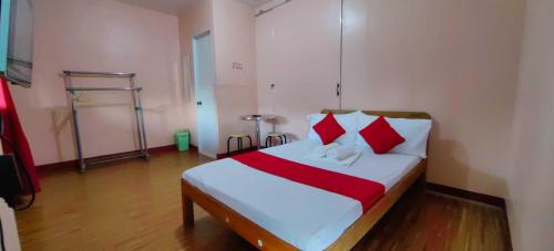 1 dormitorio con 1 cama con almohadas rojas y blancas en OYO 1038 WILLIAM HEARTS PENSION en Puerto Princesa