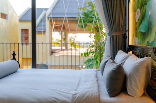 a bed with white sheets and pillows on a balcony at Lotus Villa Hoi An - 4 Bedrooms - river view - private pool in An Bang