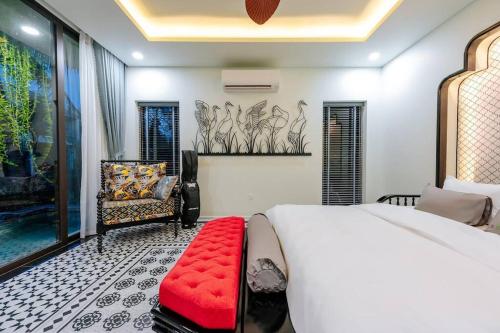 a bedroom with a white bed and a red bench at Lotus Villa Hoi An - 4 Bedrooms - river view - private pool in An Bang