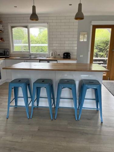 a kitchen with three blue stools at a counter at Ronny's at Tootgarook. Spacious villa, walk to beach. in Tootgarook