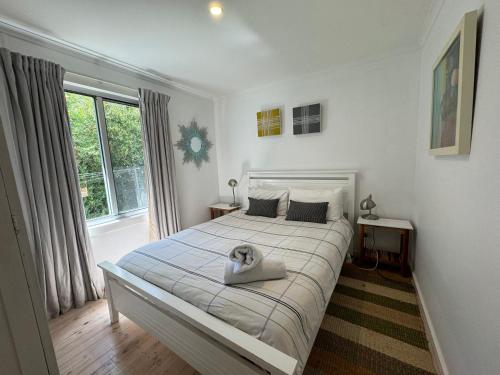 a bedroom with a large white bed with a large window at No 34 Where Nature Meets the Ocean Pet Friendly in Robe