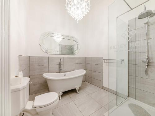 a white bathroom with a toilet and a glass shower at Buttercup Cottage - Uk45969 in Yarm