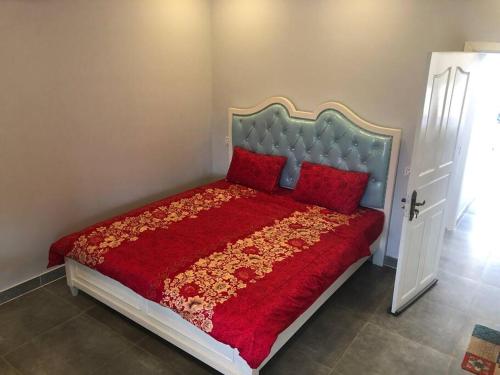 um quarto com uma cama com um cobertor vermelho e almofadas vermelhas em ‘The Greenhouse’ Nesat Village em Phumĭ Chroŭy Svay