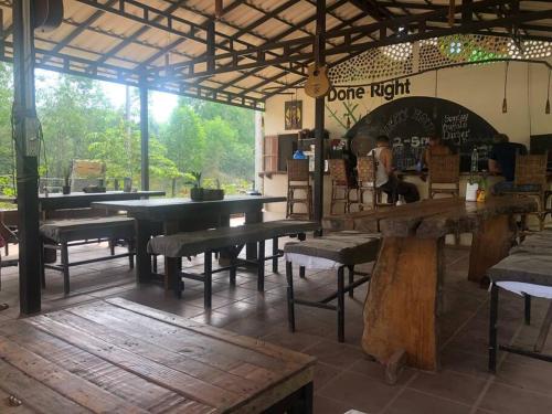 um restaurante com mesas e bancos numa sala em ‘The Greenhouse’ Nesat Village em Phumĭ Chroŭy Svay
