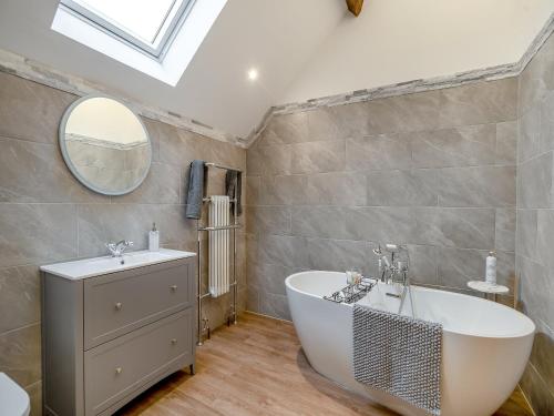 a bathroom with a tub and a sink and a mirror at Babbling Brook Barn in Abbots Bromley