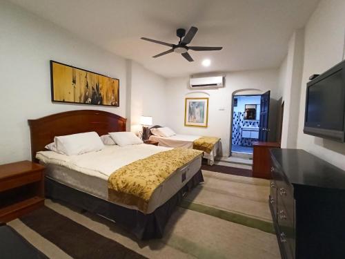 een slaapkamer met een bed en een flatscreen-tv bij ARAU HERITAGE INN in Arau