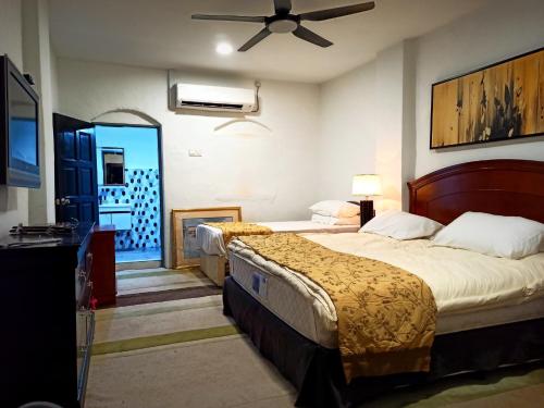 een slaapkamer met 2 bedden en een plafondventilator bij ARAU HERITAGE INN in Arau