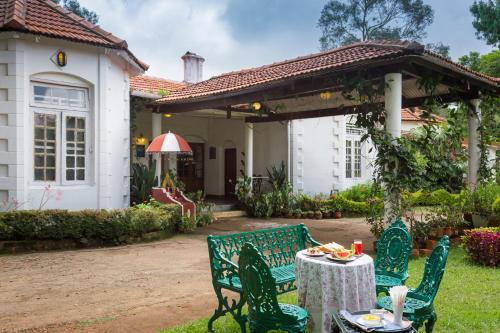 a table and chairs in front of a house at Neemrana's Wallwood Garden in Coonoor