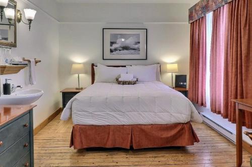ein Schlafzimmer mit einem großen Bett und einem Waschbecken in der Unterkunft Auberge de la Vieille Maison in Rimouski