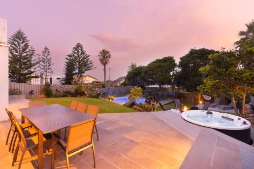 a patio with a table and chairs and a hot tub at Sea La Vie - Pet Friendly with Fireplace and Swimming Pool & Spa in Culburra Beach