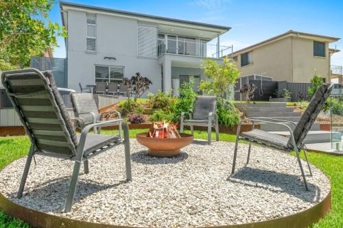 two chairs and a fire pit in front of a house at Sea La Vie - Pet Friendly with Fireplace and Swimming Pool & Spa in Culburra Beach