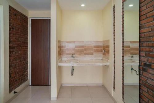 a bathroom with two sinks and a brick wall at Urbanview Hotel Omah Anin Batu by RedDoorz in Tlekung