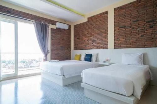 1 dormitorio con 2 camas y pared de ladrillo en Urbanview Hotel Omah Anin Batu by RedDoorz en Tlekung