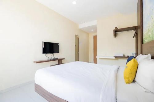 a bedroom with a white bed and a television at Urbanview Hotel Omah Anin Batu by RedDoorz in Tlekung