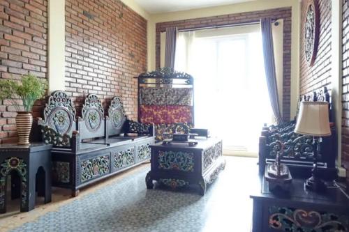 a room with black and white furniture and a brick wall at Urbanview Hotel Omah Anin Batu by RedDoorz in Tlekung