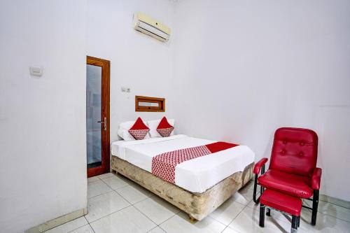 a bedroom with a bed and a red chair at OYO Life 92030 Ef Palm Guest House Family in Surabaya