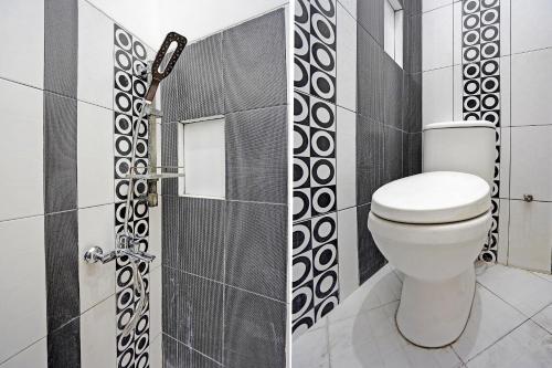 La salle de bains est pourvue d'une douche et de toilettes blanches. dans l'établissement OYO Life 92030 Ef Palm Guest House Family, à Surabaya