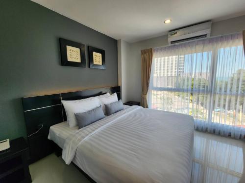 a bedroom with a large bed and a window at LHC HOTEL AND RESORT in Pattaya Central