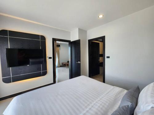 a bedroom with a white bed and a flat screen tv at LHC HOTEL AND RESORT in Pattaya Central