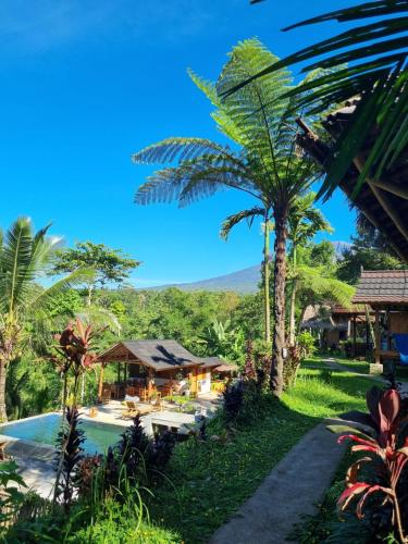 a resort with a pool and palm trees at Tetebatu Sama Sama Bungalows in Tetebatu