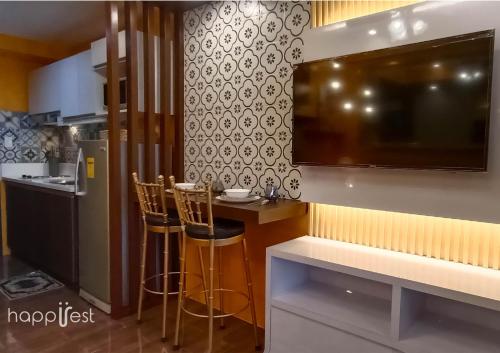 a kitchen with a bar with two chairs and a tv at Happirest at SMDC Air Residences Makati in Manila