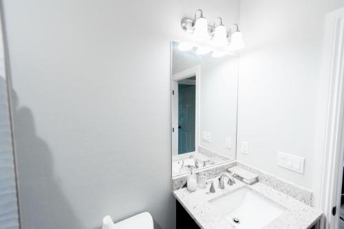 a white bathroom with a sink and a mirror at The Nesting Gem in Orangetree