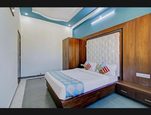 een slaapkamer met een groot bed met een houten hoofdeinde bij 7horses holidays homes in Udaipur