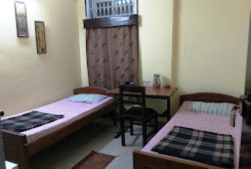 a room with two beds and a table and chairs at Hotel Prince B Guwahati in Guwahati