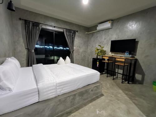 a bedroom with a large white bed and a television at The Loftel Resort in Bangkok