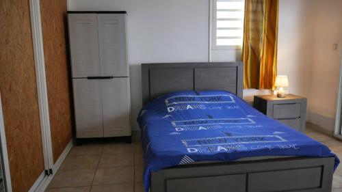 a bedroom with a bed with a blue comforter at L'Idolivier in La Plaine des Palmistes